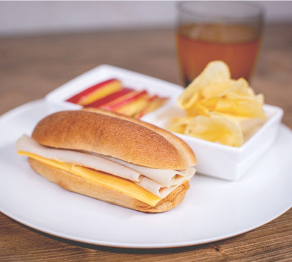 Classic Delight turkey and cheese sub with a side of sliced apples and potato chips